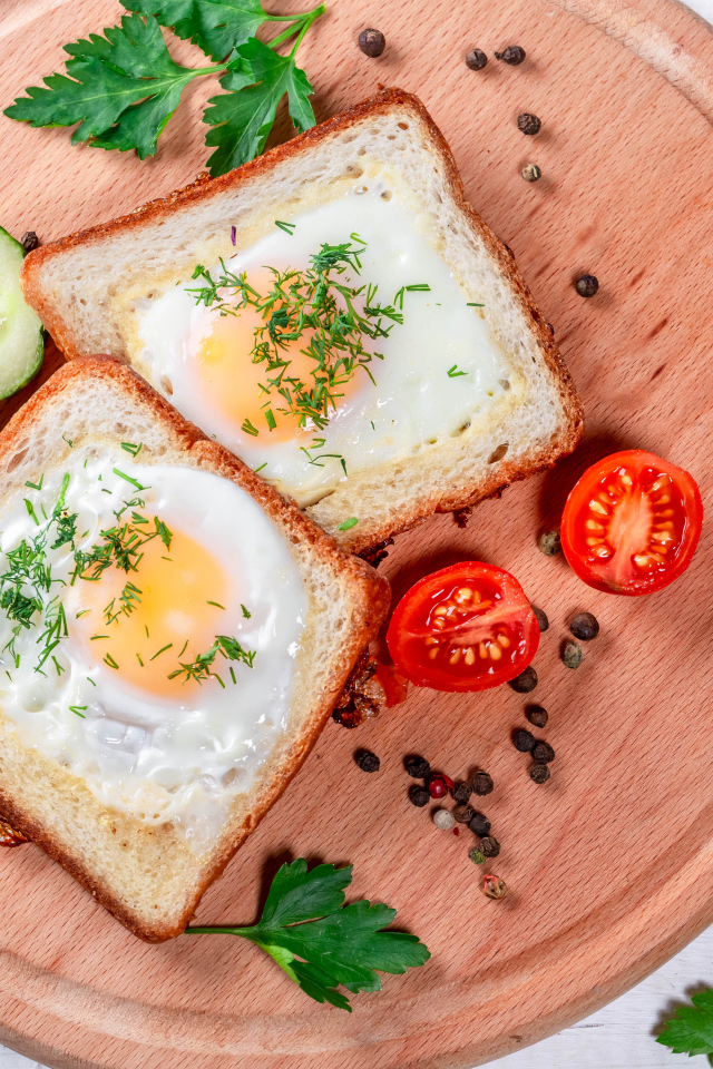 Яичница в хлебе на доске с помидорами, огурцами и петрушкой