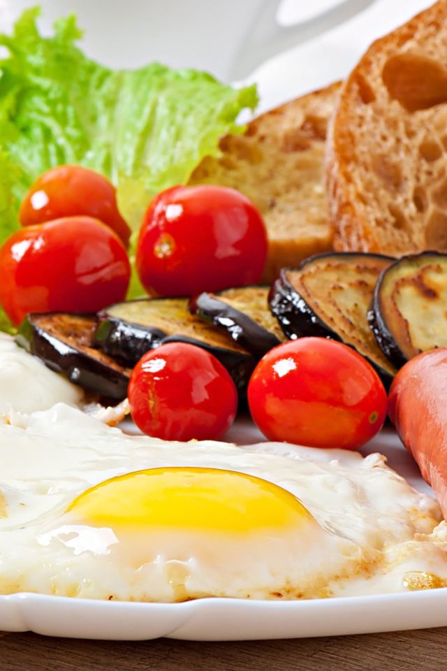 Яичница на тарелке с сосисками, овощами и хлебом