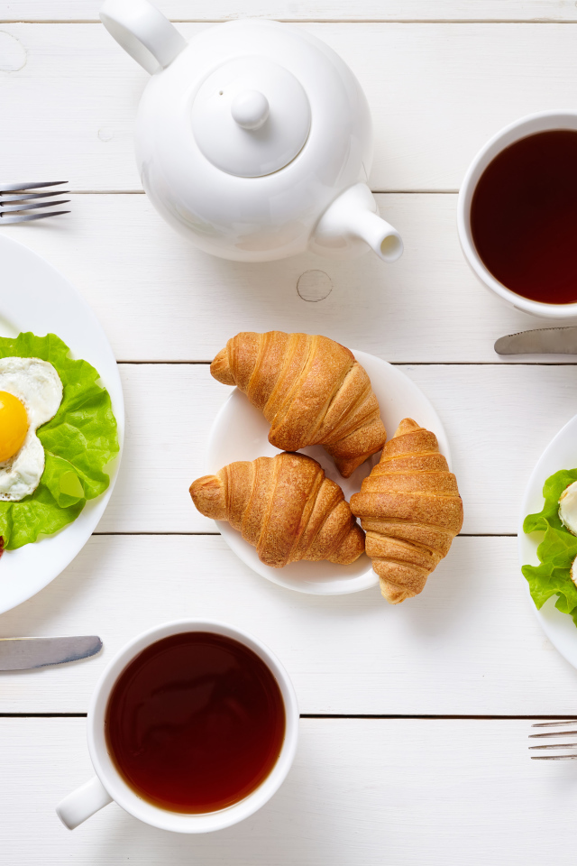 Яичница с колбасой и круассанами на столе чаем 