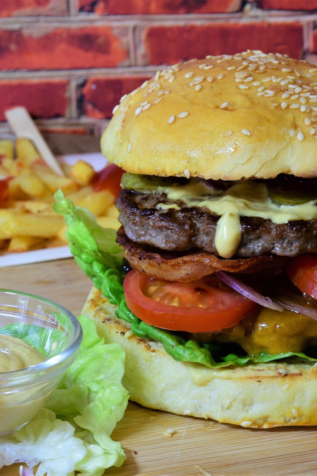 Гамбургер с беконом на столе с соусом и картофелем фри