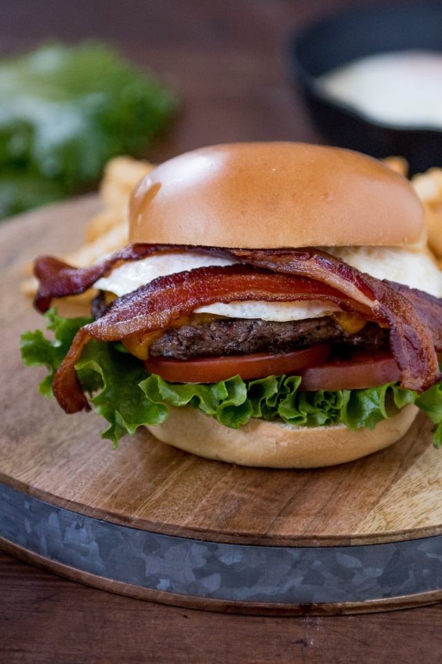 Гамбургер с беконом на столе с овощами
