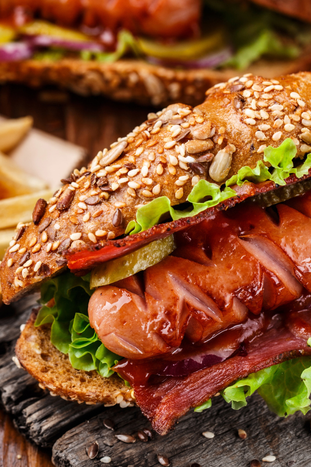 Хотдог с сосиской и беконом на столе с картофелем фри 