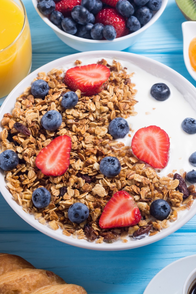 Мюсли с ягодами и молоком в тарелке на столе к завтраку