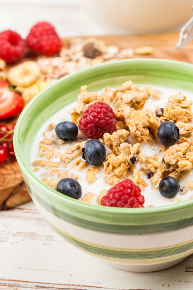 Мюсли с молоком и ягодами на столе к завтраку