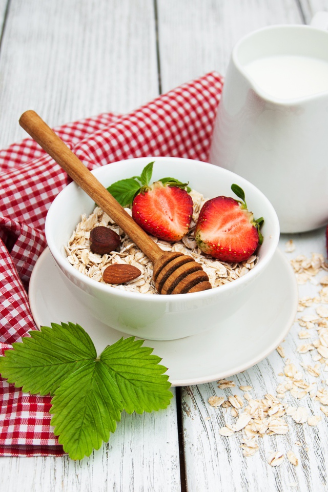 Овсяная каша на столе с молоком и клубникой