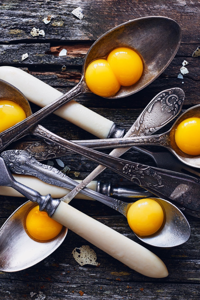 Старые ложки с желтками на деревянном столе