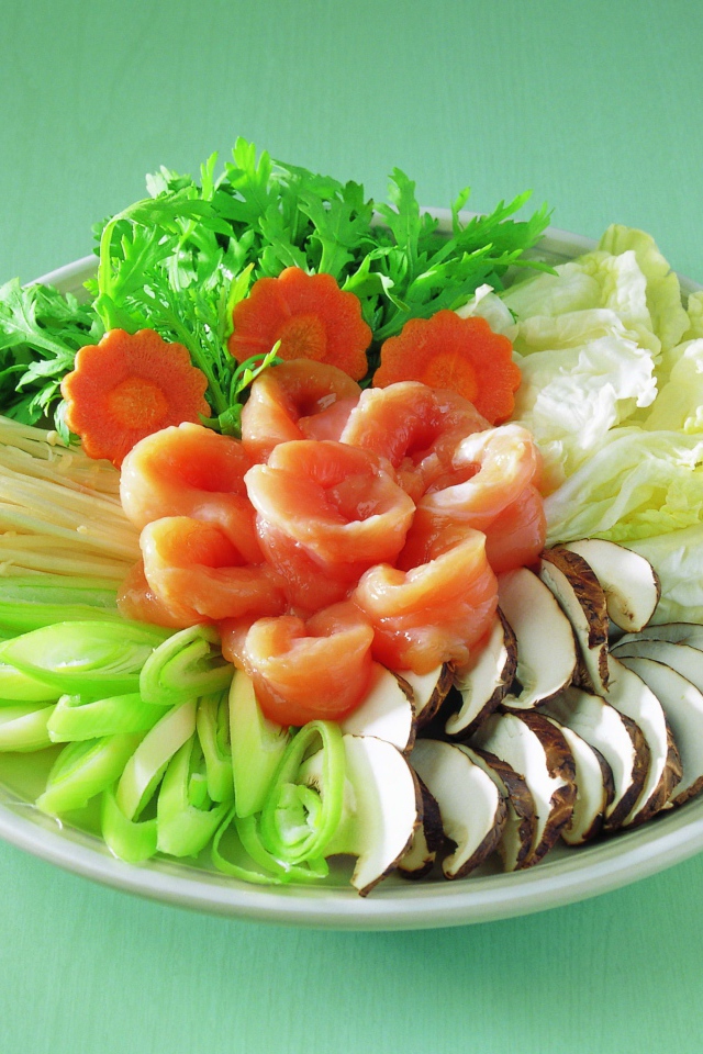 Тарелка с овощами и красной рыбой на зеленом фоне