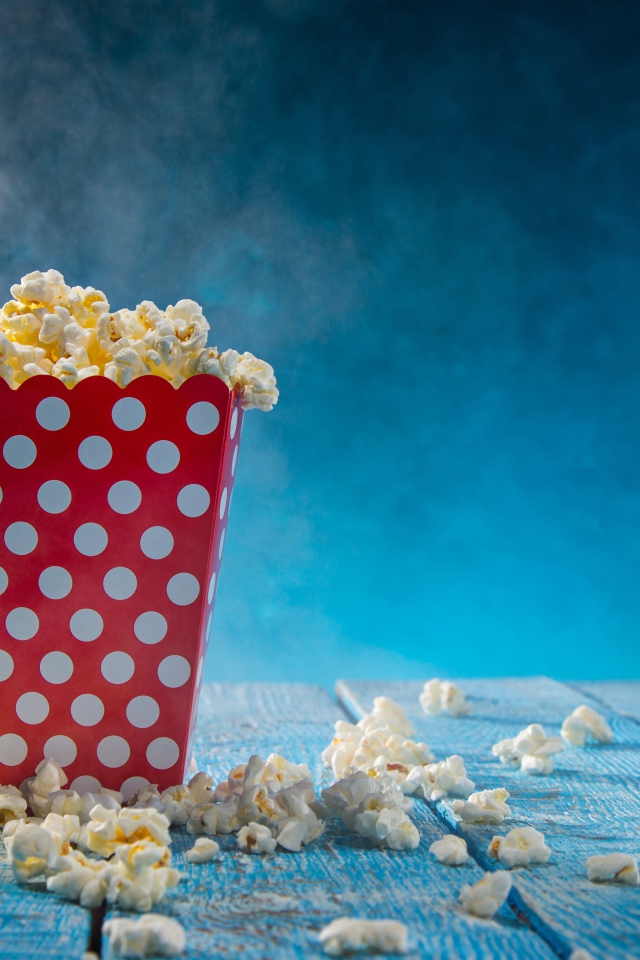 Попкорн в картонном пакете на голубом столе 