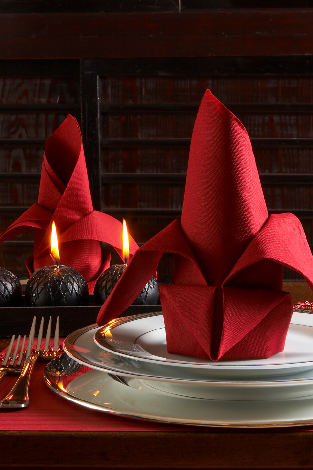 Красная салфетка на тарелке на столе с бокалами вина и свечами