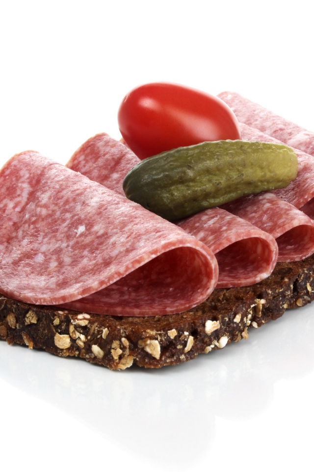 Бутерброд с черным хлебом, колбасой, соленым огурцом и помидором на белом фоне