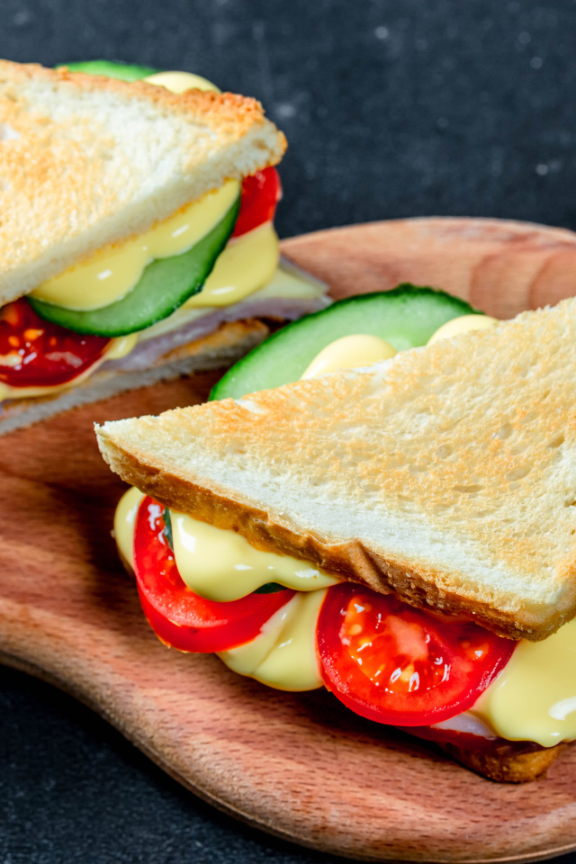 Сэндвич с сыром, помидорами и огурцами на столе