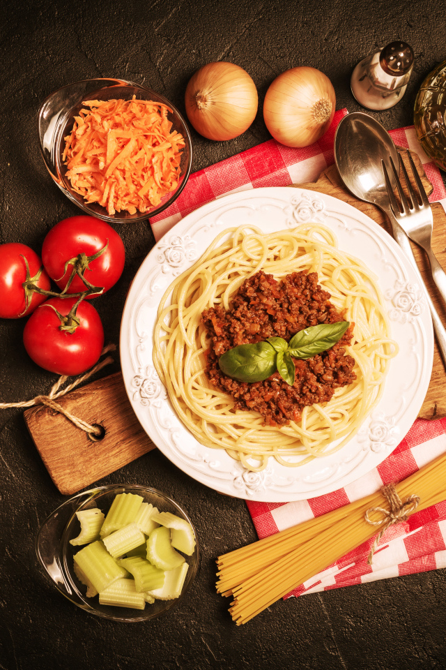 Спагетти с фаршем на столе с овощами