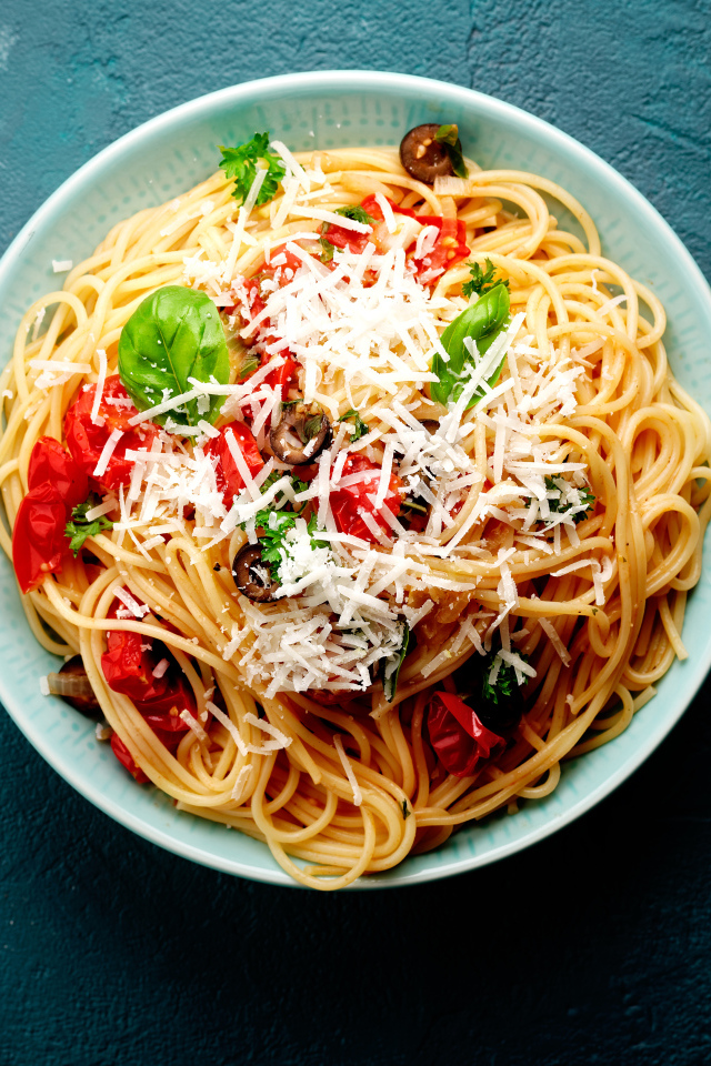 Спагетти с помидорами, сыром и базилик на столе