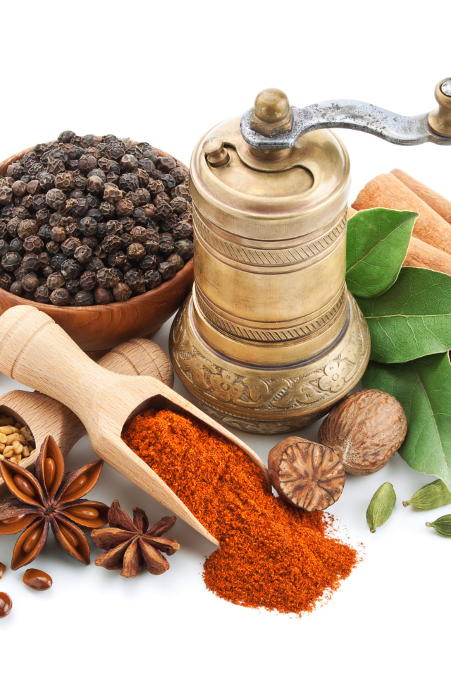 Пряные специи на столе с мельницей на белом фоне