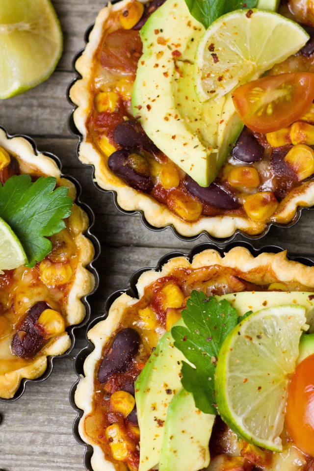 Тарталетки с блюдом, кусочками авокадо и лайма на столе