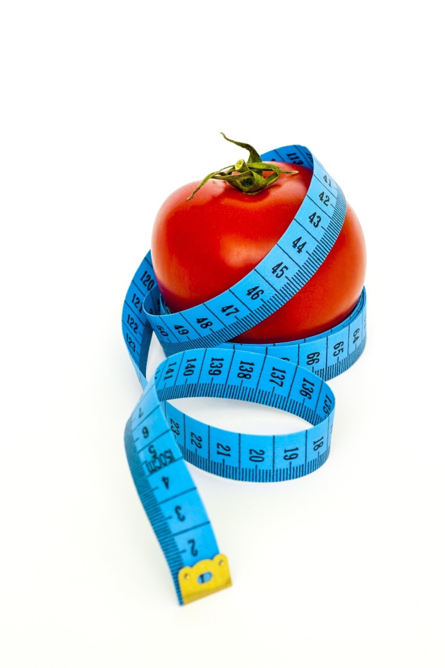 Помидор с голубым сантиметром на белом фоне