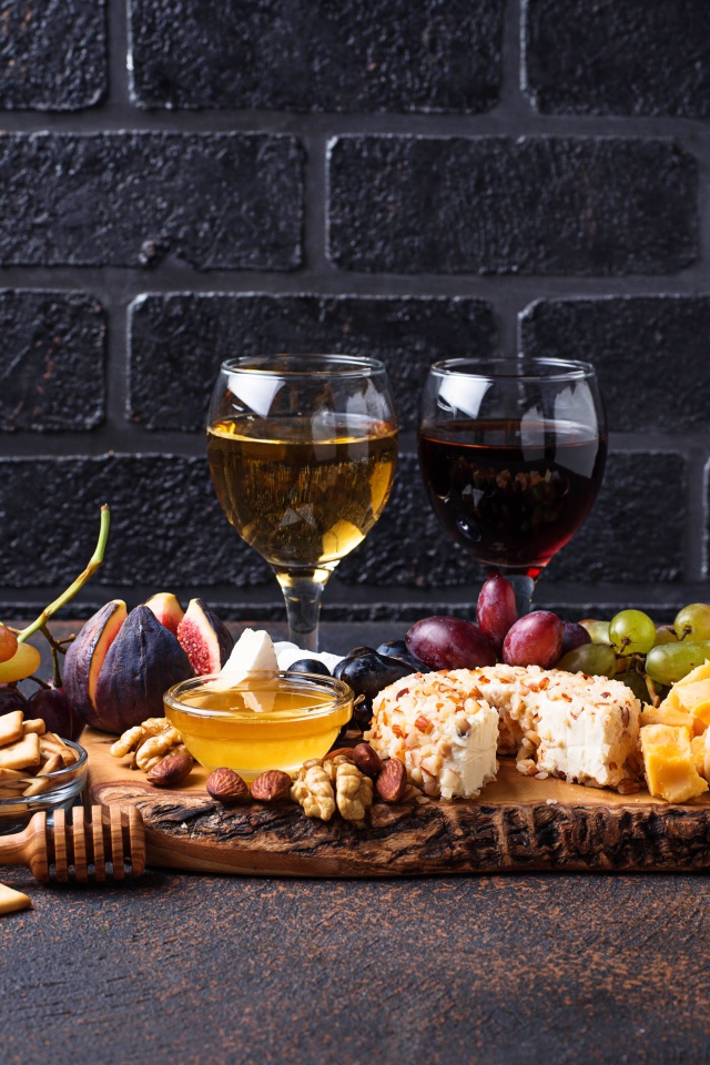 Два бокала вина на столе с сыром, инжиром и виноградом