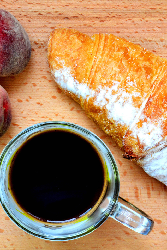 Два персика на столе с кофе и круассаном