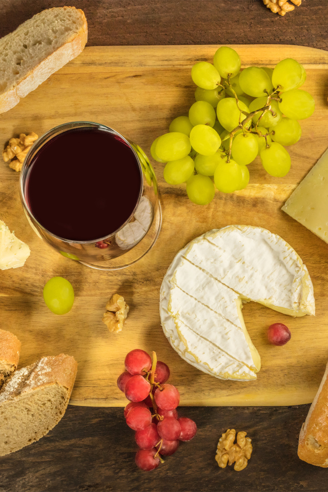 Вино, сыр, виноград и багет на столе 
