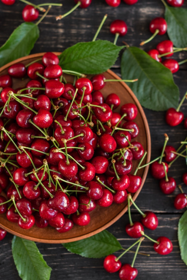 Много спелой красной черешне в миске на столе