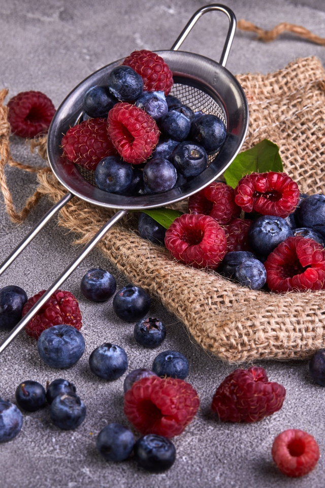 Ягоды черники и малины на столе с ситом