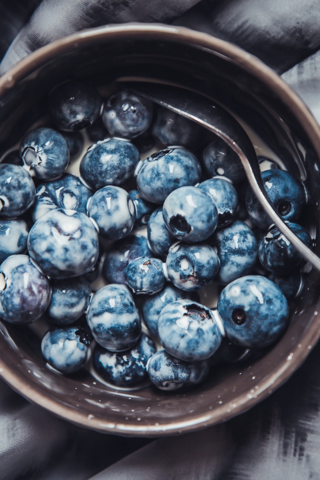 Черника в миске с йогуртом и ложкой