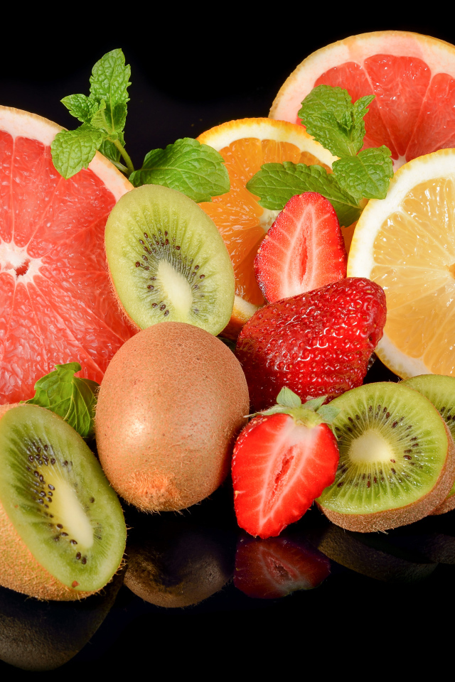 Цитрусовые фрукты на черном фоне с ягодами клубники 