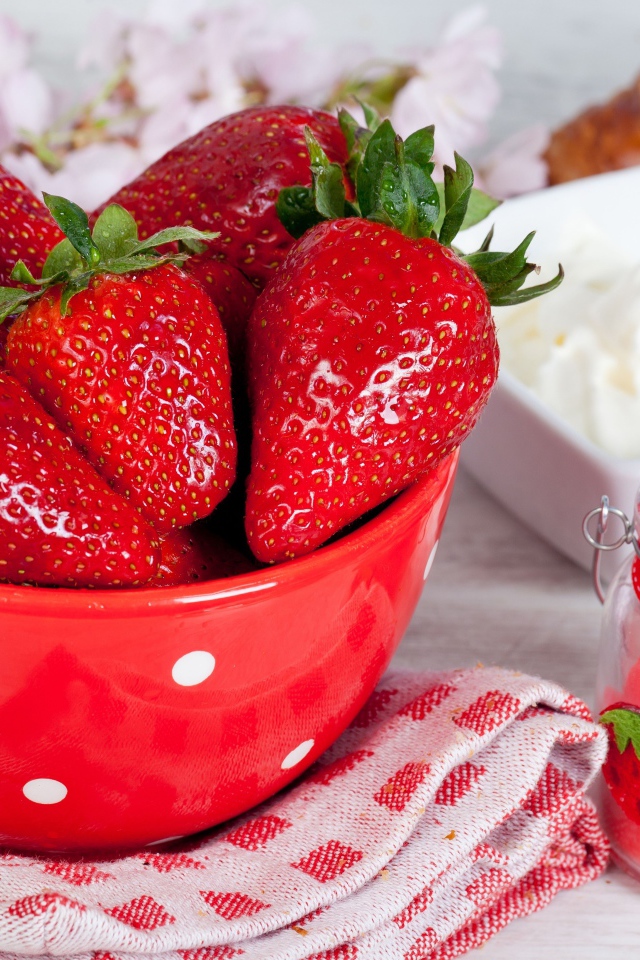 Свежие ягоды клубники в красной миске на столе