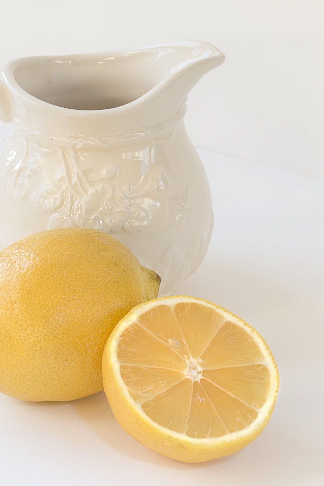 Лимон с белым кувшином на сером фоне