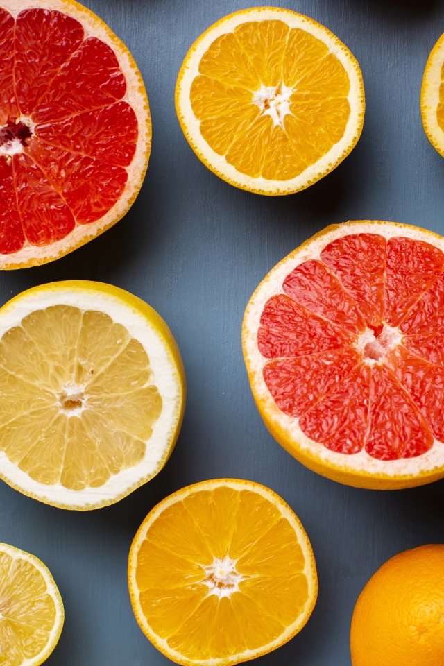 Лимоны, грепфрукты и апельсины на сером фоне