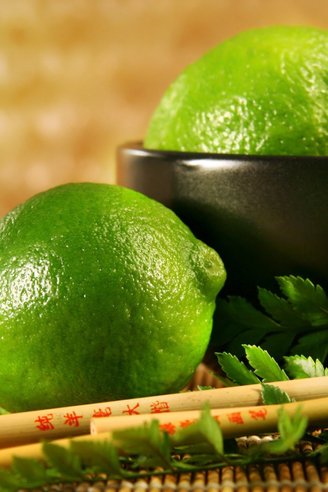 Лаймы на столе с палочками и листьями