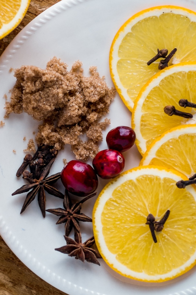 Круги апельсина на тарелке с сахаром, корицей и бадьяном