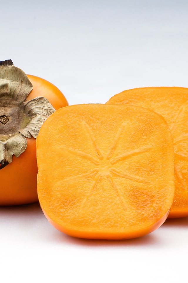 Оранжевая хурма на сером фоне крупным планом