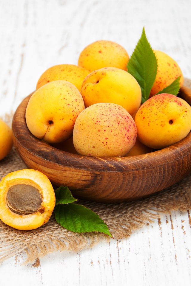 Спелые абрикосы в деревянной миске на столе