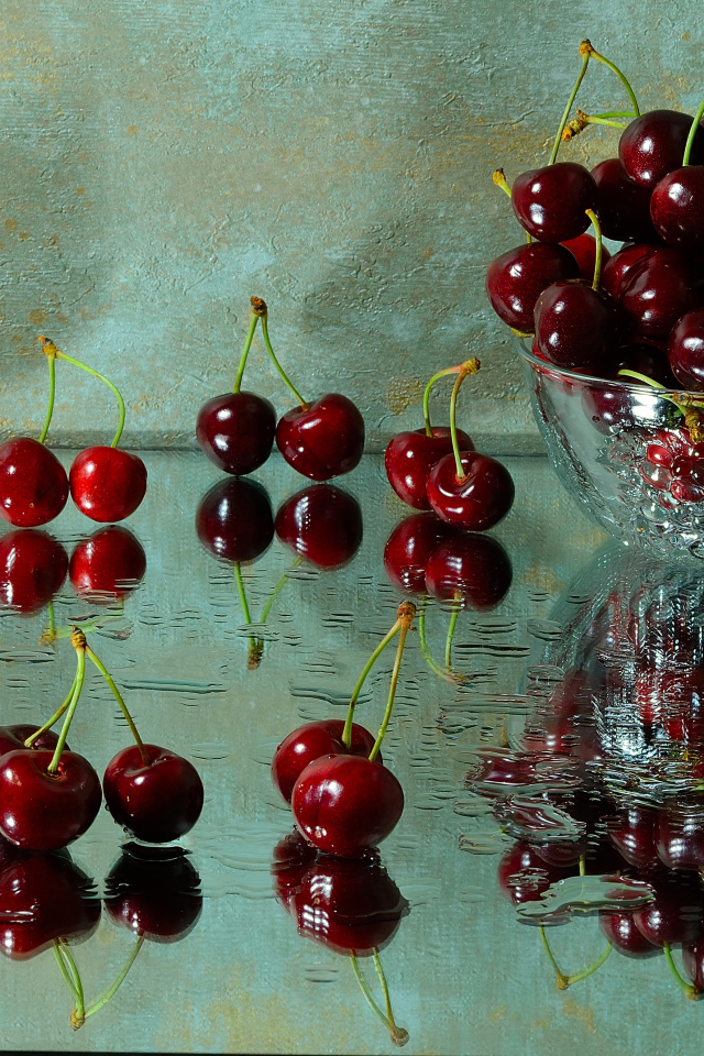 Спелые красные черешни отражаются в поверхности стола