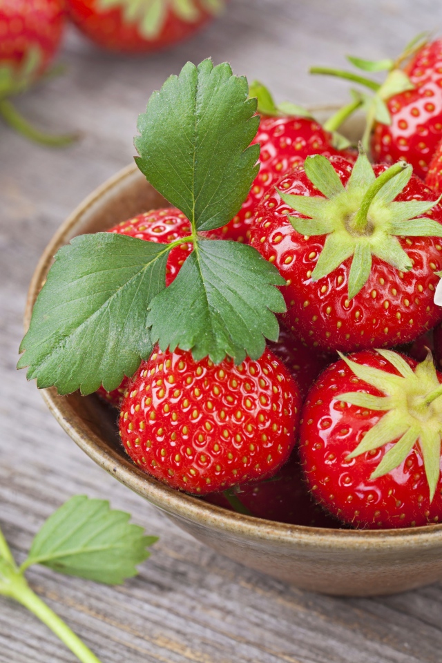 Спелая красная клубника в миске на столе 