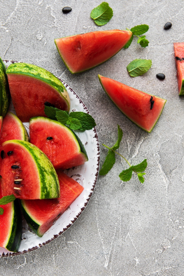 Полосатый арбуз нарезан кусочками на тарелке