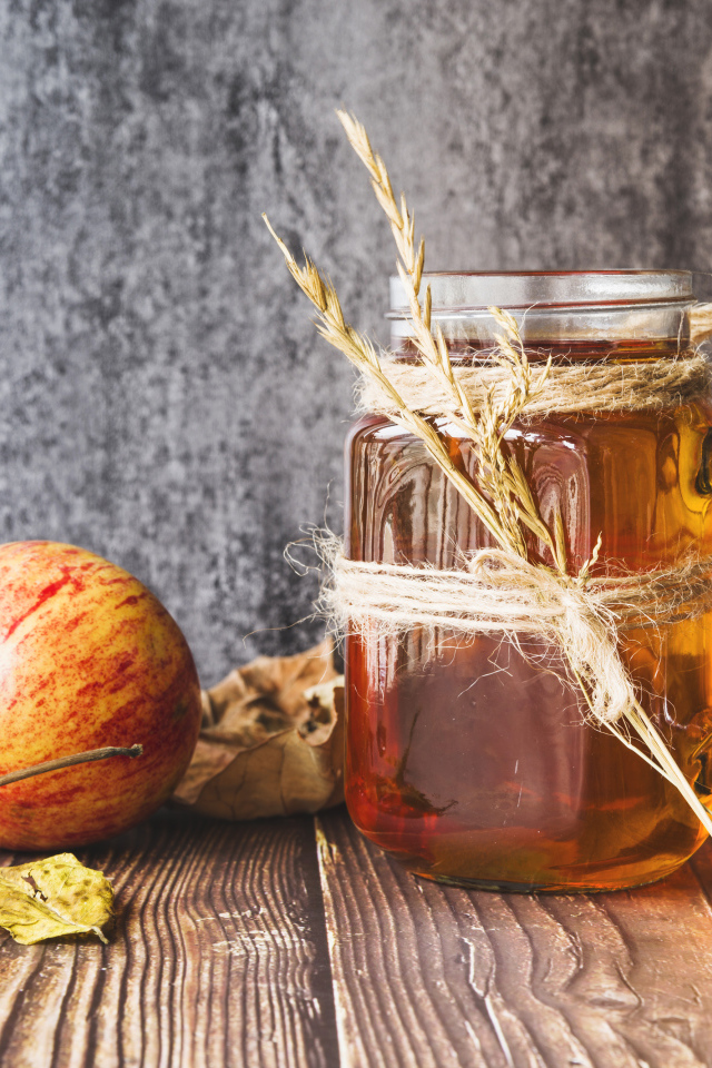 Три яблока с медом на столе на сером фоне