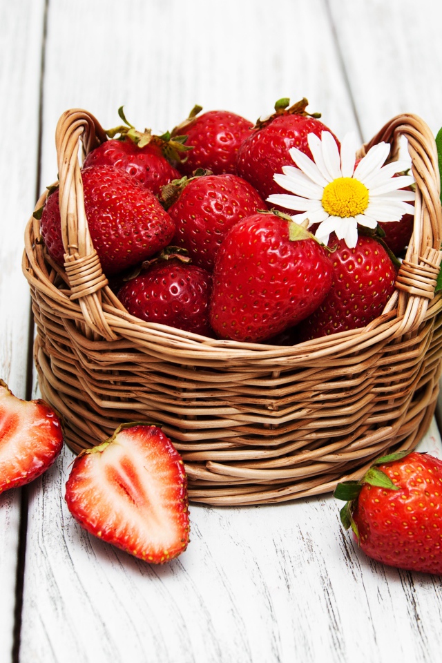 Плетеная корзинка с клубникой, ромашкой и зелеными листьями