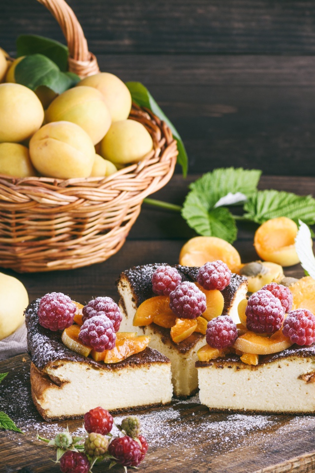 Вкусный фруктово - ягодный пирог на столе с корзиной с абрикосами