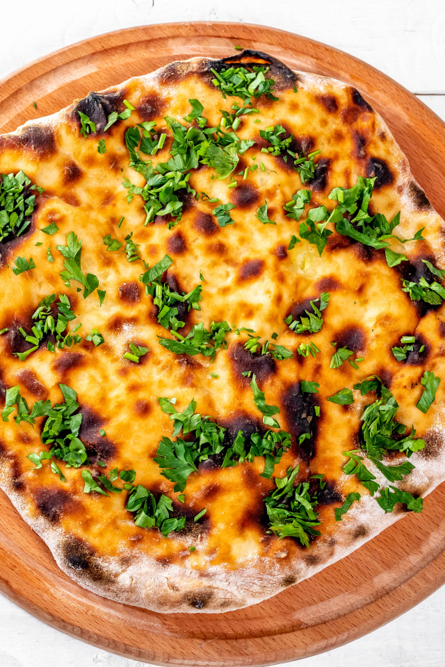 Пирог с сыром и зеленью на доске 