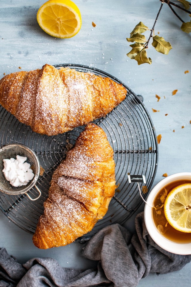 Два свежих круассана на столе с чаем