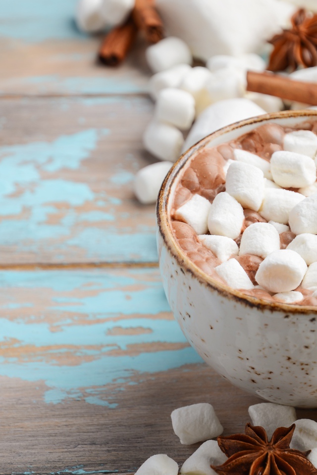 Чашка какао с маршмеллоу на столе с корицей и сладостями