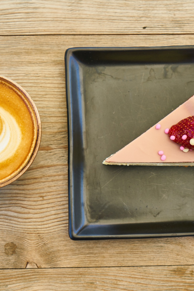 Кусок торта на черной тарелке с кофе