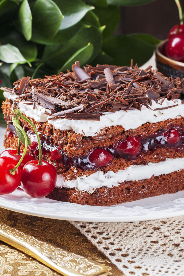 Кусок торта с вишней, шоколадной крошкой на столе с розой