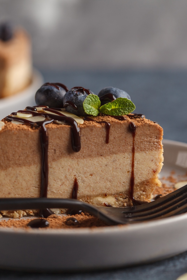 Кусок чизкейка с черникой и шоколадом на тарелке с вилкой