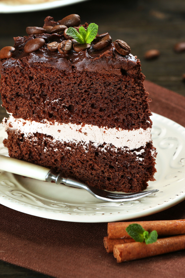 Кусок шоколадного торта с кремом и зернами кофе