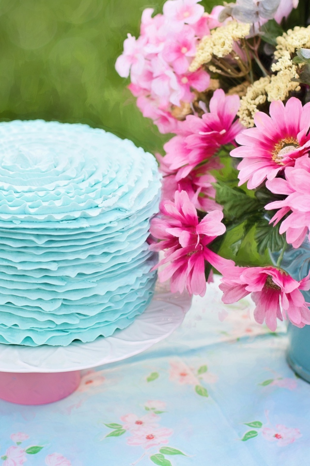 Красивый торт с голубой глазурью на столе с букетом