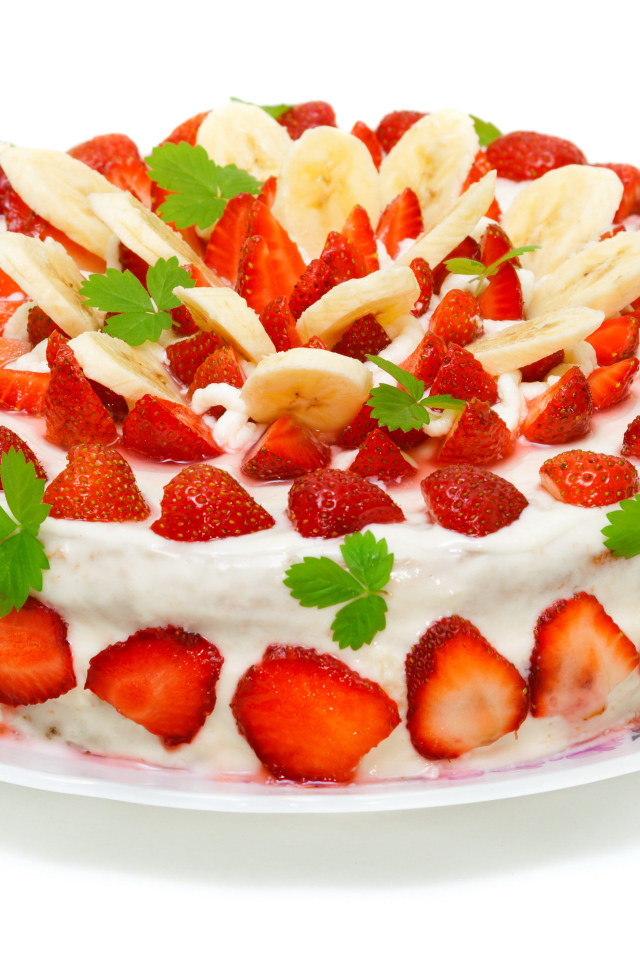 Большой торт с клубникой и бананами на белом фоне