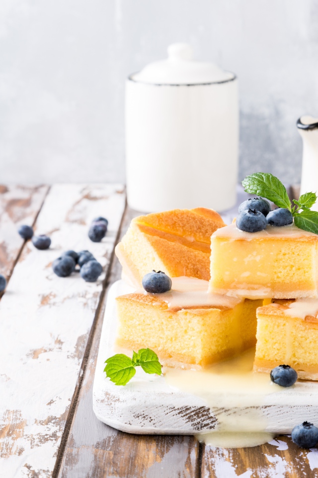 Кусочки бисквитного пирожного на столе с ягодами черники